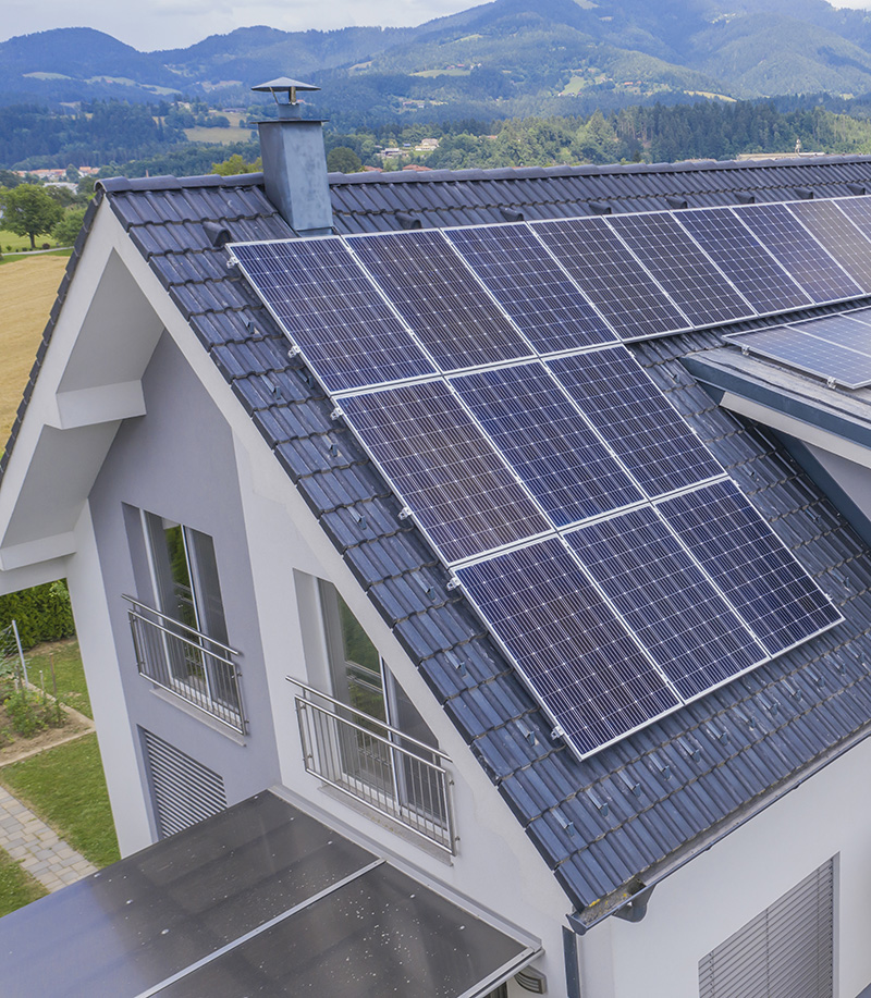 A high angle shot of a private house situated in a valley with solar panels on the roof