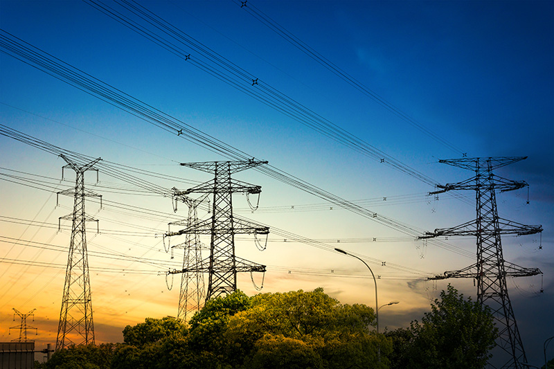 Sun setting behind the silhouette of electricity pylons