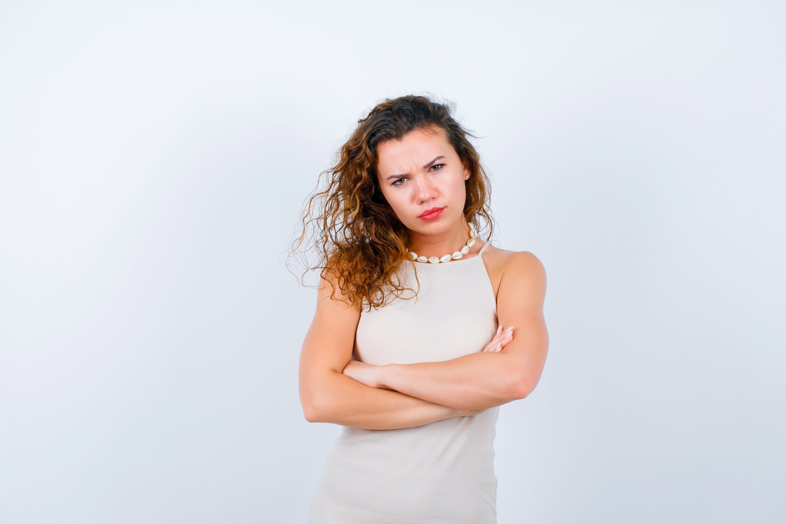 Angry young girl is looking at camera by crossing arms on white background Angry young girl is looking at camera by crossing arms on white background